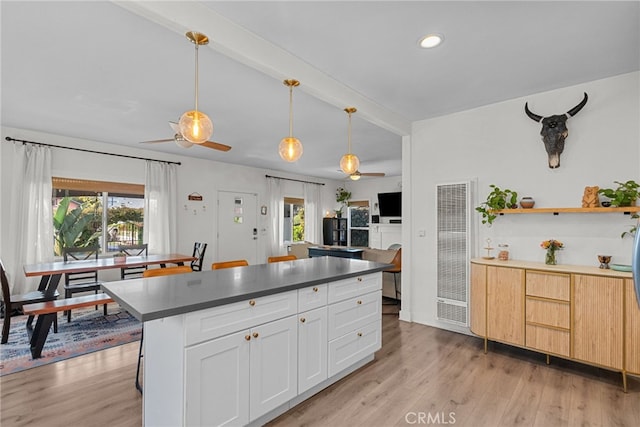kitchen featuring light wood-type flooring, beamed ceiling, dark countertops, and a ceiling fan