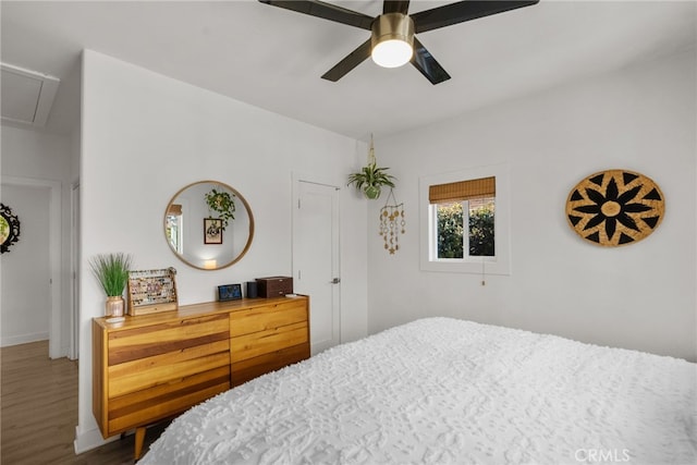 bedroom with ceiling fan, attic access, and wood finished floors