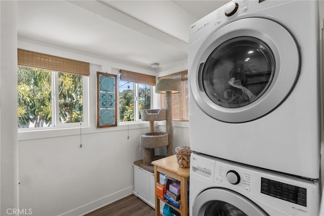washroom with baseboards, stacked washer and dryer, laundry area, and wood finished floors