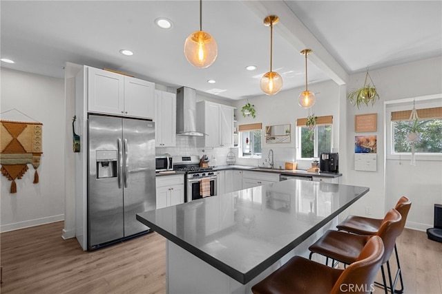 kitchen with tasteful backsplash, wall chimney exhaust hood, plenty of natural light, and stainless steel appliances