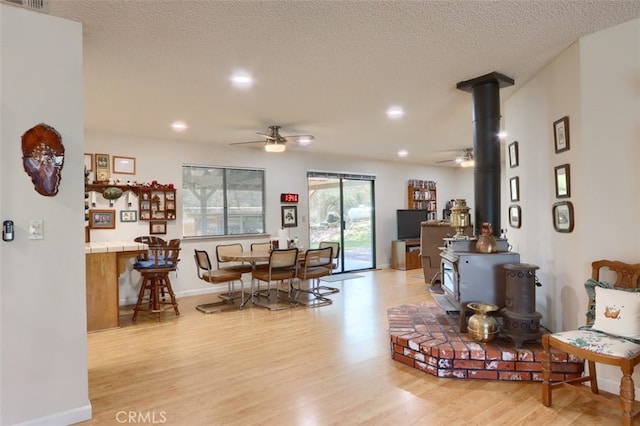 44410 Quail Ct, Coarsegold, CA 93614 - living room featuring a textured ceiling, a wood stove, a ceiling fan, and light wood finished floors