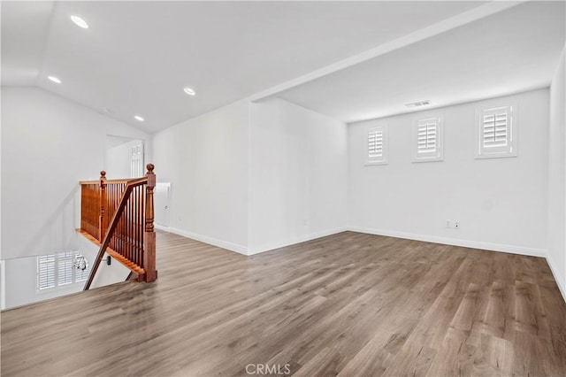 empty room featuring recessed lighting, lofted ceiling, baseboards, and wood finished floors