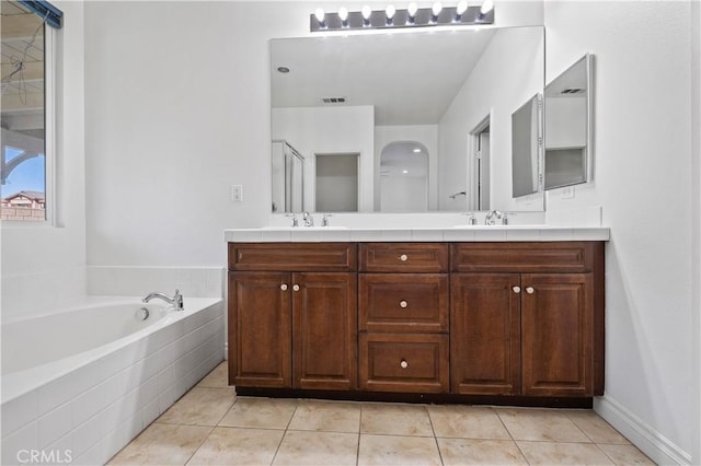 full bathroom with tile patterned floors, a garden tub, a sink, and double vanity