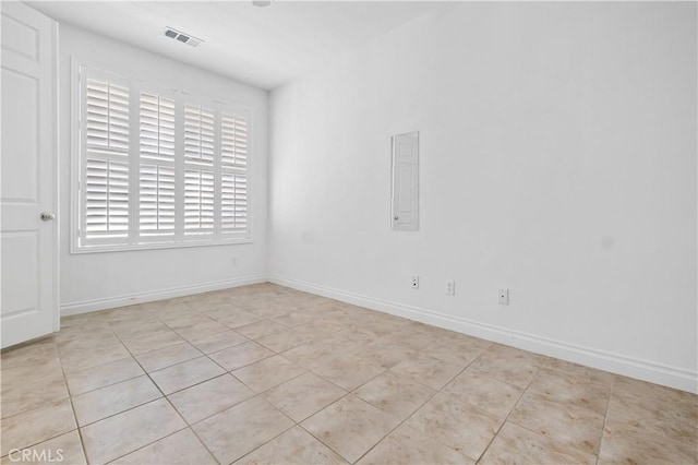 empty room featuring light tile patterned floors, baseboards, visible vents, and a wealth of natural light