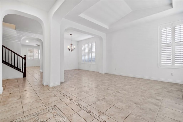 unfurnished room featuring arched walkways, a raised ceiling, a chandelier, and light tile patterned floors