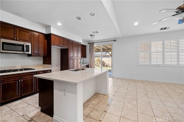 kitchen featuring light countertops, visible vents, stainless steel microwave, gas stovetop, and ceiling fan