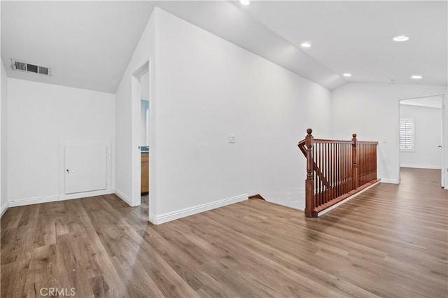 spare room featuring visible vents, baseboards, recessed lighting, wood finished floors, and lofted ceiling