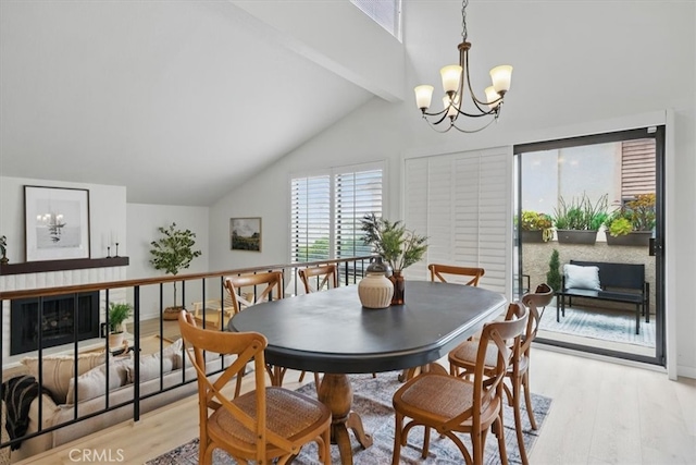 dining space with beamed ceiling, light wood finished floors, an inviting chandelier, and high vaulted ceiling