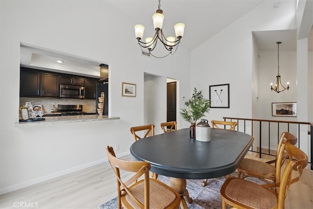 dining space featuring high vaulted ceiling, baseboards, a chandelier, and light wood-style floors