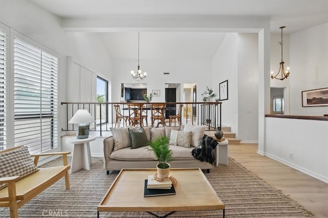living area with baseboards, an inviting chandelier, beam ceiling, light wood finished floors, and high vaulted ceiling