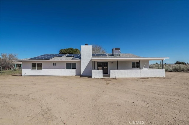15029 Larch St, Hesperia, CA 92345 - rear view of house with central AC unit, stucco siding, a chimney, and roof mounted solar panels