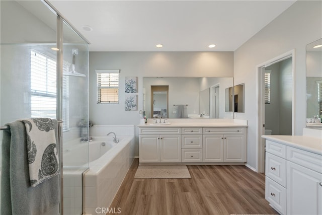 bathroom featuring a bath, toilet, vanity, and wood finished floors