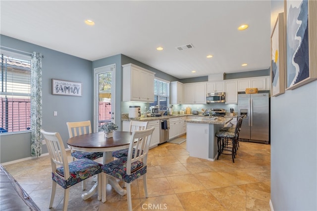kitchen with white cabinets, recessed lighting, a kitchen breakfast bar, stainless steel appliances, and visible vents
