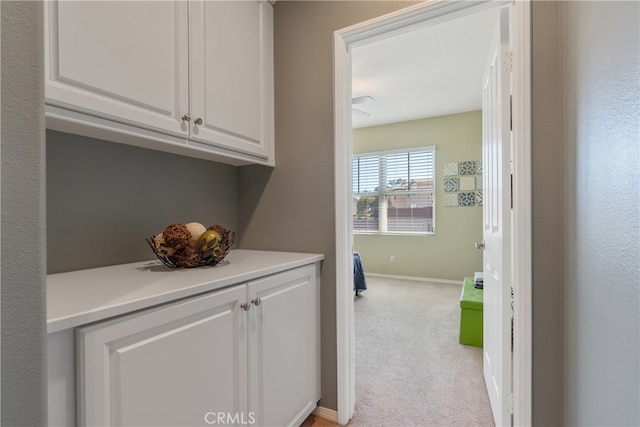 corridor featuring baseboards and light colored carpet