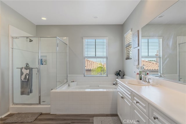 full bathroom with a bath, wood finished floors, vanity, and a stall shower