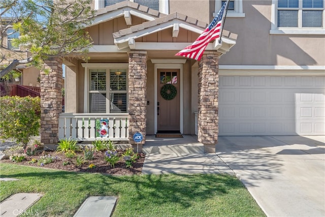 doorway to property with a porch, concrete driveway, a garage, and stucco siding