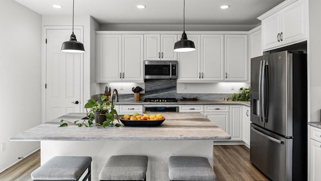 kitchen featuring pendant lighting, white cabinets, appliances with stainless steel finishes, and dark wood-type flooring