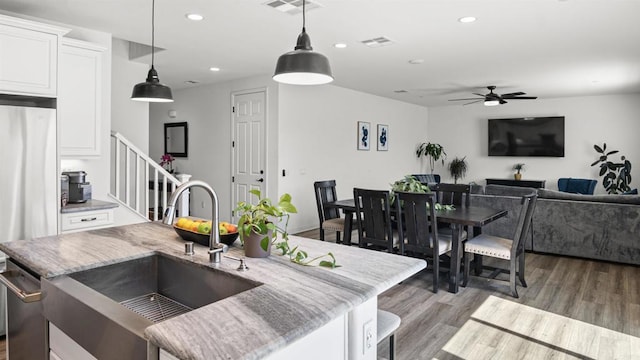 kitchen featuring wood finished floors, visible vents, stainless steel fridge, and a sink