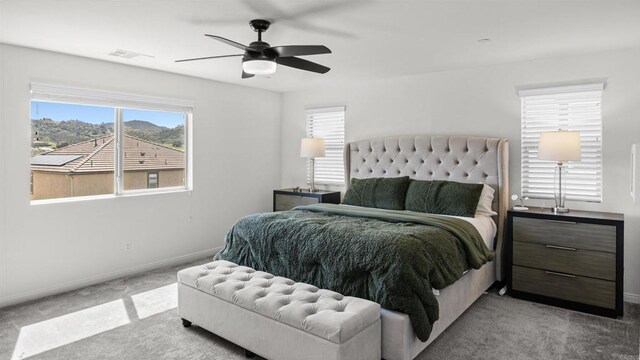 bedroom with baseboards, visible vents, light carpet, and multiple windows