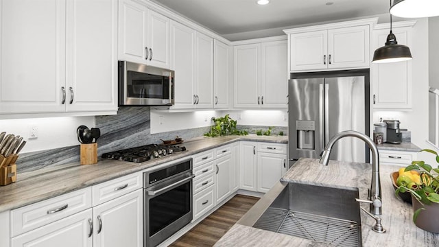 kitchen featuring hanging light fixtures, a sink, white cabinets, and appliances with stainless steel finishes