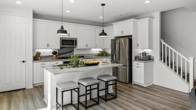 kitchen with white cabinets, wood finished floors, and stainless steel appliances
