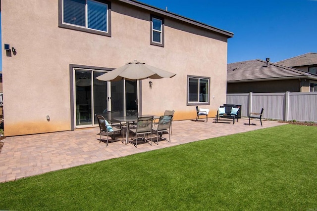 back of property featuring an outdoor hangout area, a patio area, stucco siding, a lawn, and fence