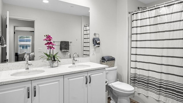 full bathroom with recessed lighting, toilet, double vanity, and a sink