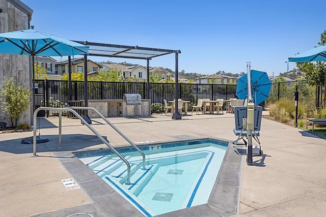 view of swimming pool featuring a residential view, a patio area, exterior kitchen, and fence