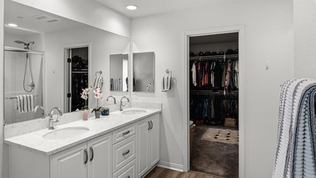 bathroom featuring double vanity, a sink, wood finished floors, and a spacious closet