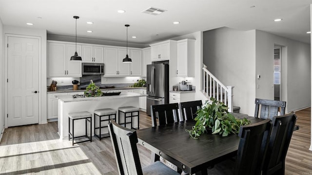 dining space with visible vents, stairs, light wood finished floors, and recessed lighting