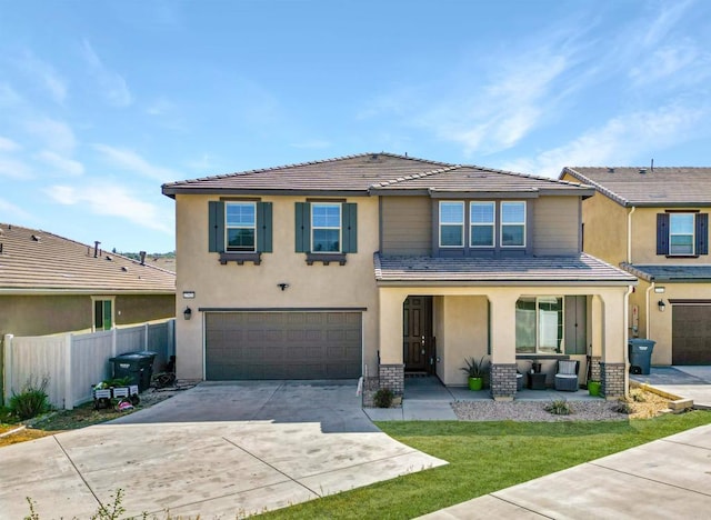 traditional-style house with a garage, a tiled roof, concrete driveway, stucco siding, and fence