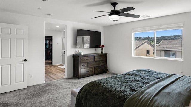 carpeted bedroom featuring baseboards, a spacious closet, visible vents, and ceiling fan
