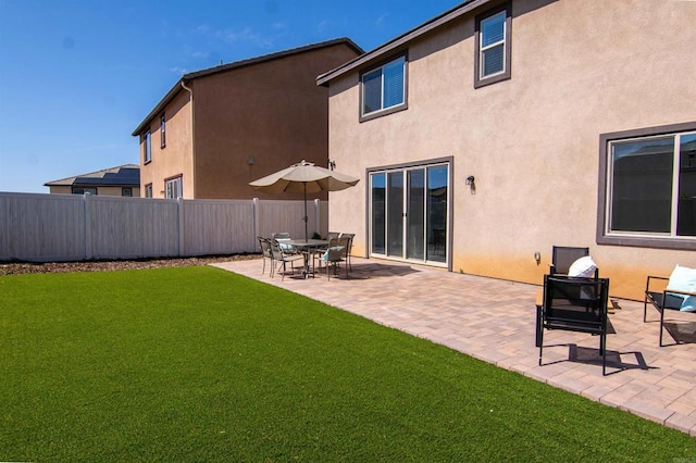 back of house with a patio area, a yard, stucco siding, and fence