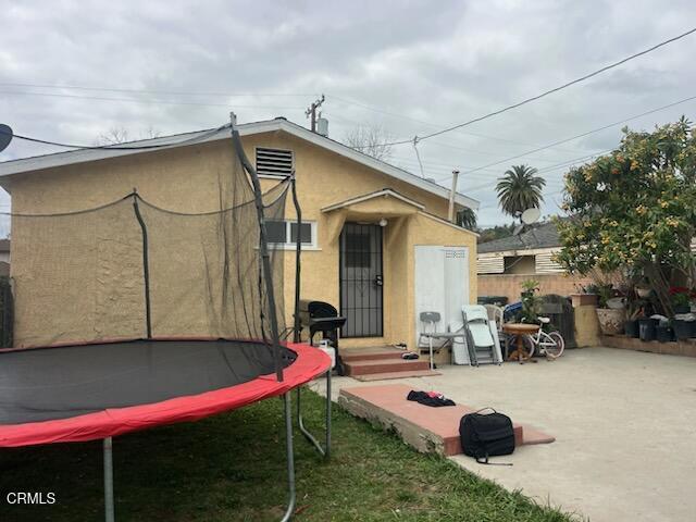 321 Walnut St, Santa Paula, CA 93060 - rear view of house featuring a patio area, a trampoline, a lawn, fence, and stucco siding