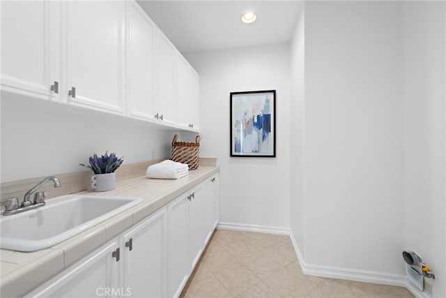 washroom with baseboards, recessed lighting, and a sink