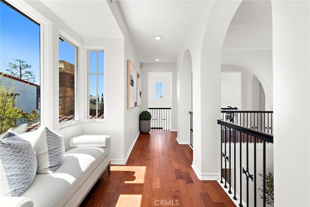 hallway with baseboards, recessed lighting, wood-type flooring, and plenty of natural light