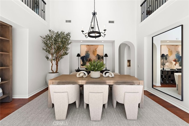 dining space with visible vents, baseboards, dark wood-style floors, and a high ceiling