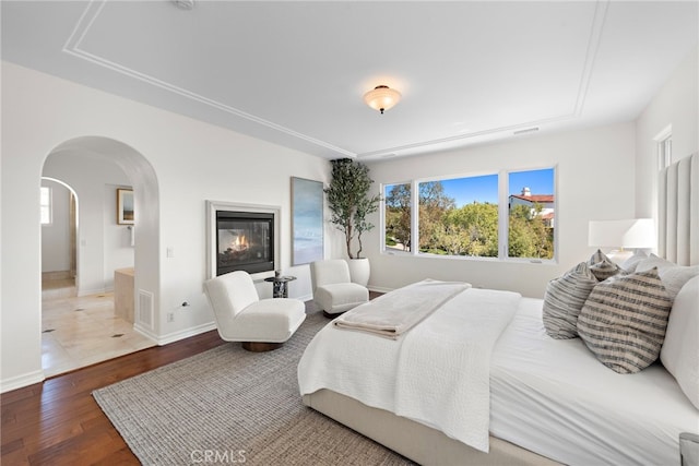 bedroom with visible vents, wood finished floors, arched walkways, and multiple windows