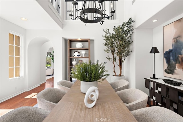 dining area with baseboards, recessed lighting, arched walkways, and wood finished floors