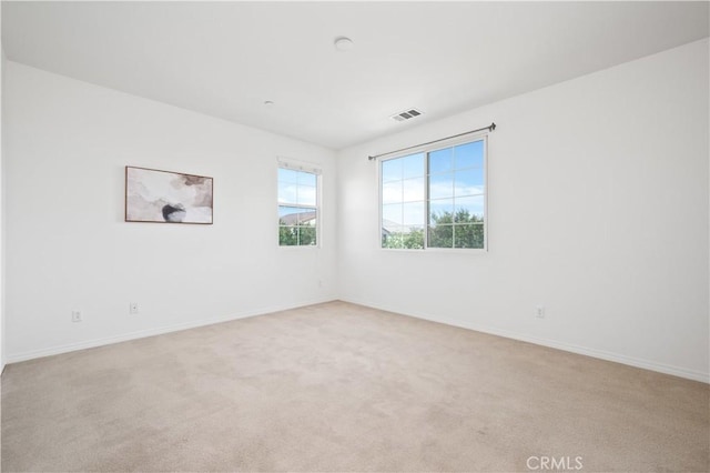 unfurnished room with visible vents, baseboards, and light carpet