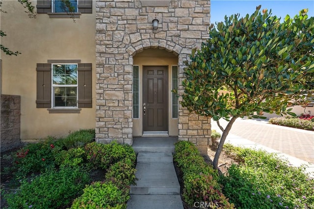 view of exterior entry featuring stucco siding and stone siding