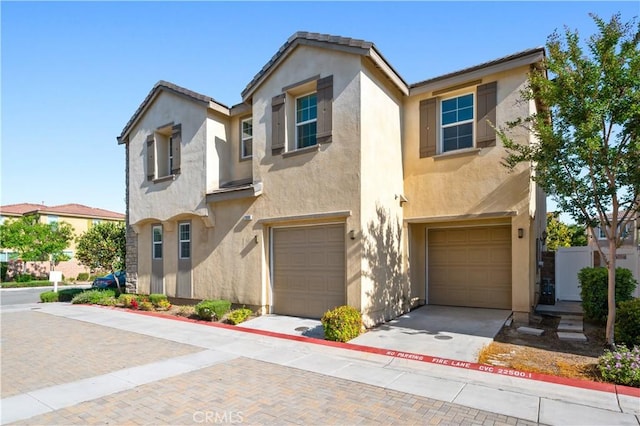 view of front of house featuring stucco siding, decorative driveway, and an attached garage
