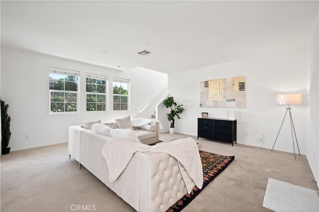 living area featuring visible vents, baseboards, light colored carpet, and stairs