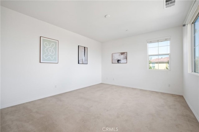 empty room featuring light carpet, baseboards, and visible vents