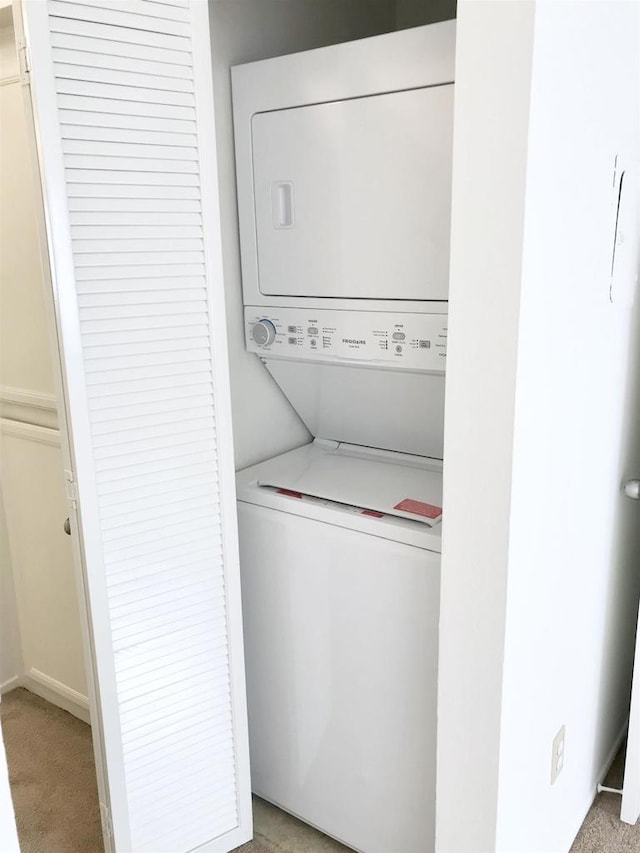 laundry room with laundry area, stacked washer / drying machine, and light carpet