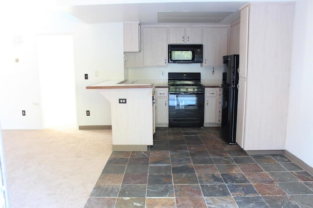kitchen featuring dark carpet, a peninsula, stone finish flooring, and black appliances