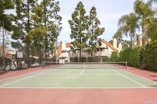 view of tennis court featuring community basketball court and fence