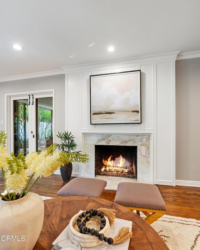 living room featuring baseboards, crown molding, recessed lighting, wood finished floors, and a premium fireplace