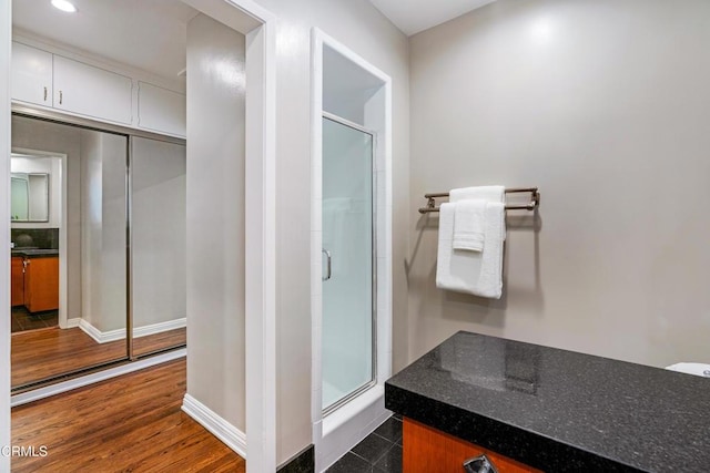 bathroom with baseboards, a stall shower, and wood finished floors