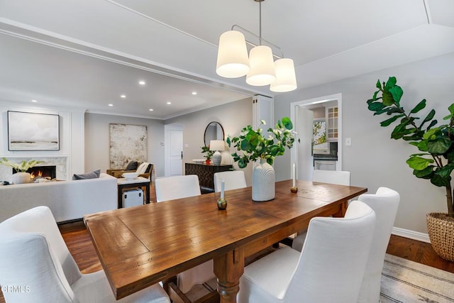 dining area featuring baseboards, recessed lighting, crown molding, a high end fireplace, and wood finished floors